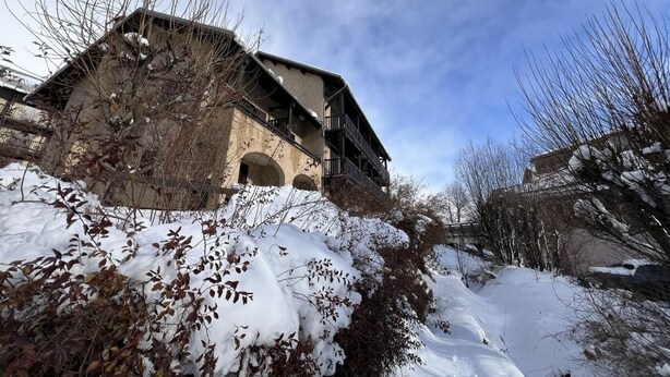 A rustic building with a stone facade and multiple balconies, surrounded by snow-covered ground and leafless trees. - Wifi, 1st floor, balcony, tv, ski locker, 34m², Serre Chevalier (Le Monêtier-les-Bains)