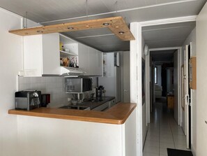 Una cocina moderna con encimera de madera, armarios blancos, microondas y tostadora.
