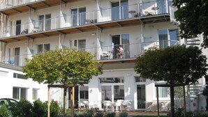 A multi-story residential building with balconies, outdoor seating, and a garden area. - City Hotel (Linz)