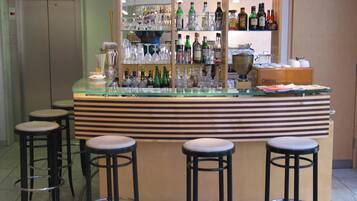 Eine Bar mit einer Glastheke, mehreren Barhocker und Regalen voller Spirituosenflaschen.