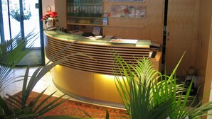 A reception area with a curved desk, a glass display case, and a wall-mounted map. - City Hotel (Linz)