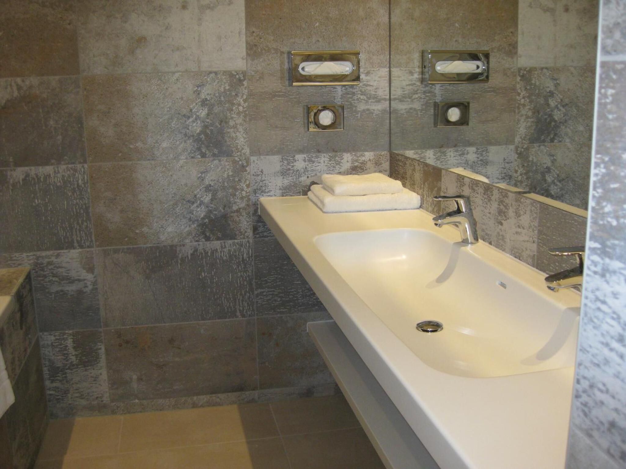 A modern bathroom with a large bathtub, a sink, and a mirror.
