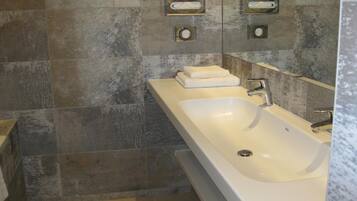A modern bathroom with a large bathtub, a sink, and a mirror.