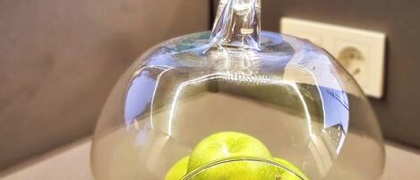 A glass dome containing green apples on a countertop.