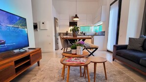 A modern living room with a flat-screen TV, wooden furniture, and a kitchen in the background. - Suelo Flat Villa for Family (Bodrum)