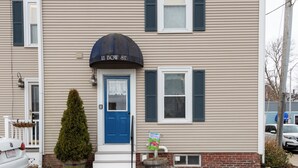 Un bâtiment à deux étages avec une porte bleue, une pancarte d’accueil et une boîte aux lettres.