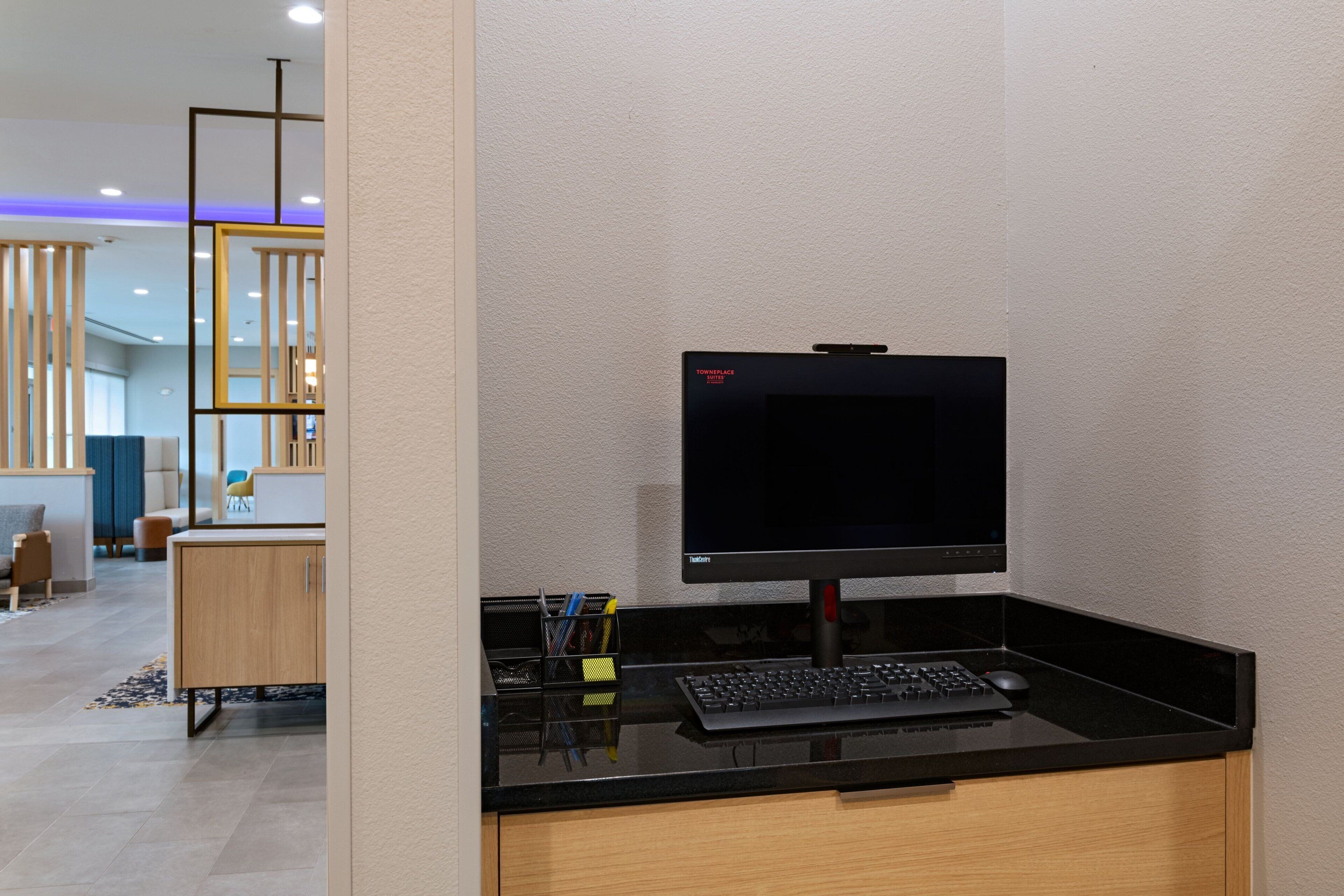 A modern office space with a black desk, a computer monitor, and a keyboard.