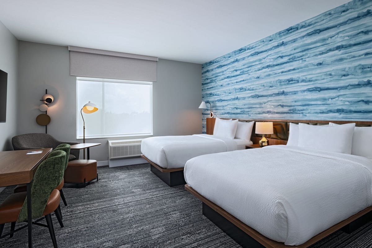 Une chambre d’hôtel avec deux lits, un bureau et une chaise.