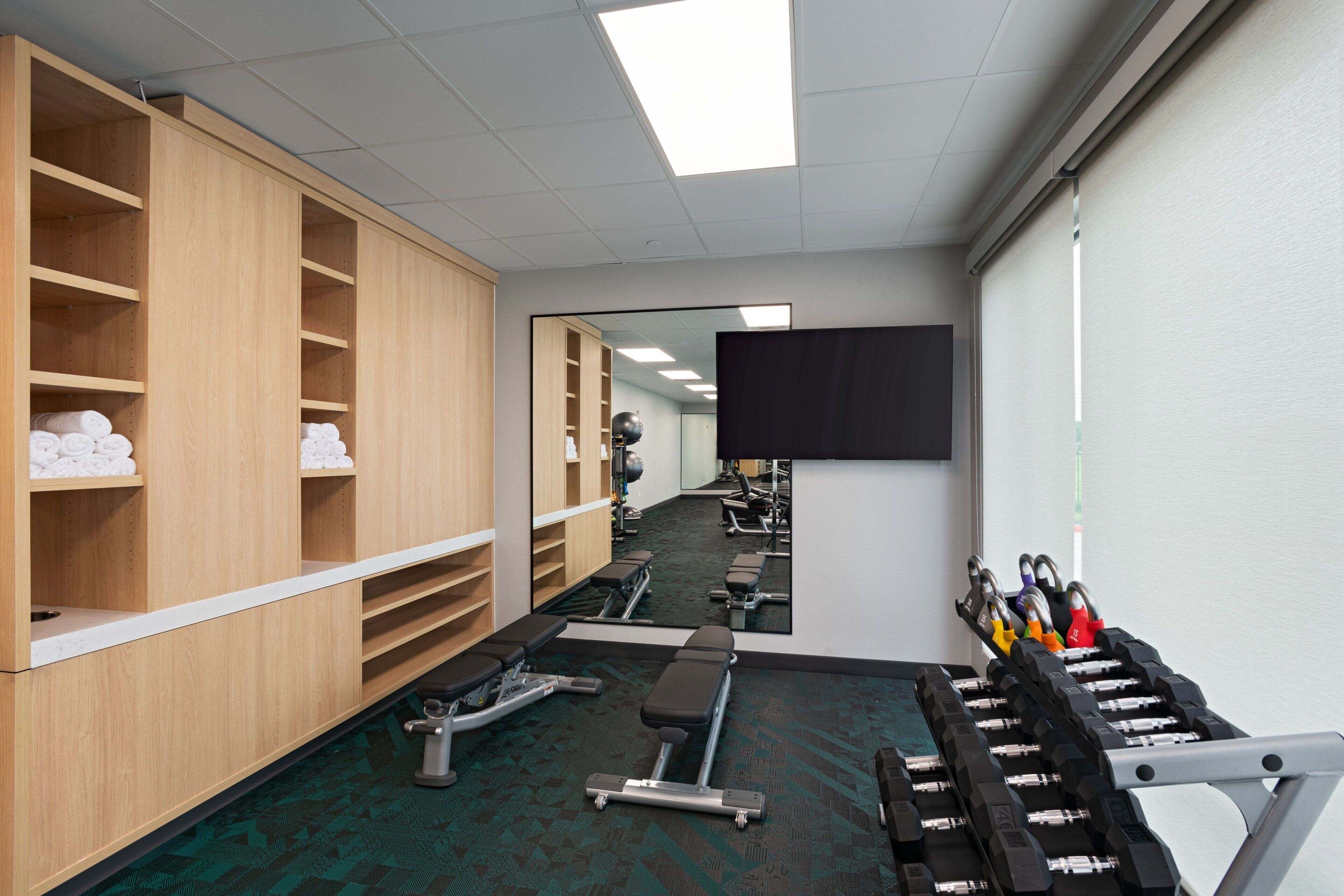 A gym with exercise equipment, a mirror, and wooden lockers.