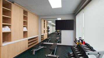 A gym with exercise equipment, a mirror, and wooden lockers.