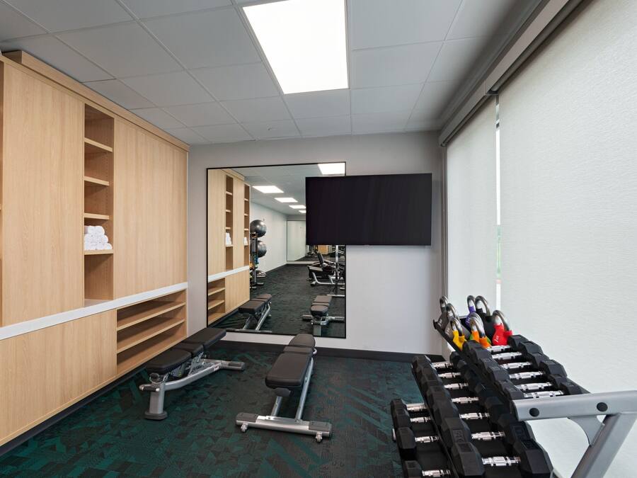 A gym with exercise equipment, a mirror, and wooden lockers.