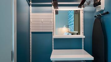 Un baño con pared azul, estante blanco, espejo y toallero.