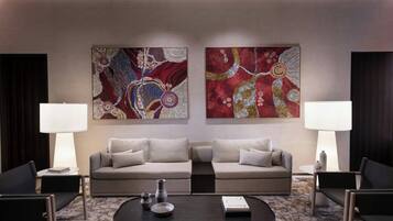 Un salon moderne comprenant un ensemble de canapés, deux tables d’appoint avec des lampes, une table basse et des tableaux abstraits accrochés au mur.