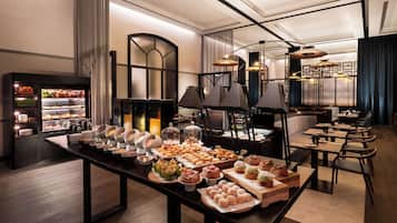 A buffet setup with various food items and a seating area with tables and chairs.