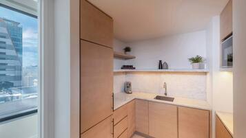 Een moderne keuken met houten kastjes, een marmeren aanrechtblad en een raam met uitzicht op een stadsbeeld.