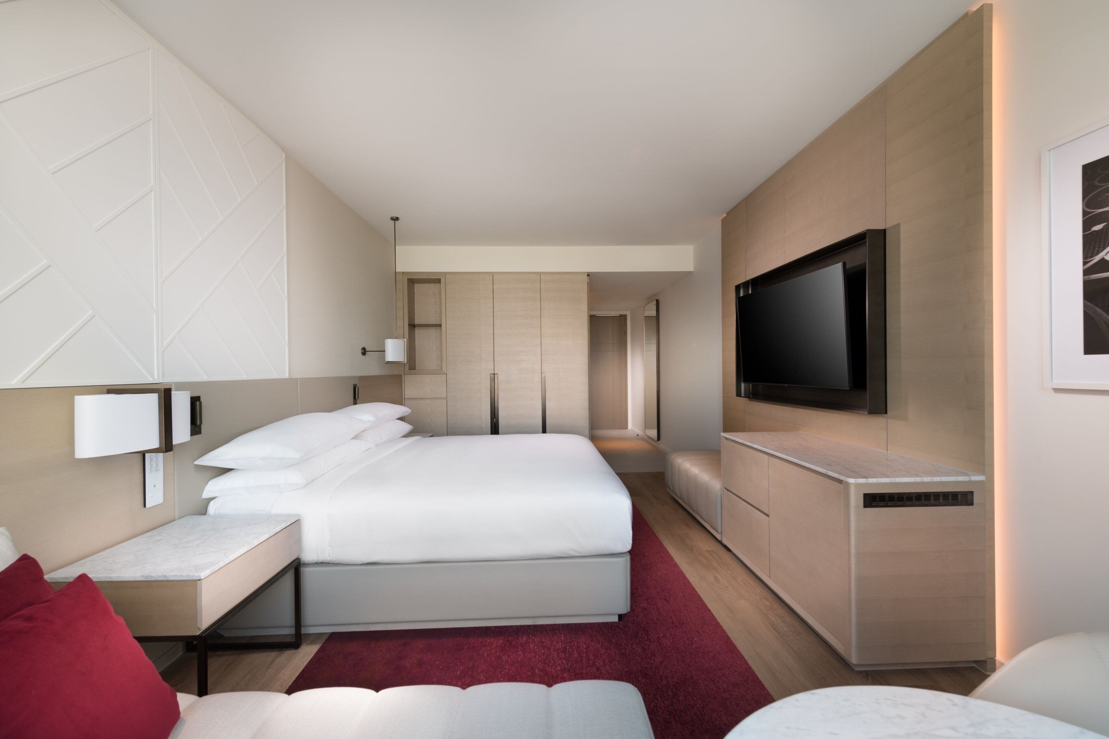 Une chambre d’hôtel moderne dotée d’un grand lit, d’un téléviseur à écran plat, d’une table de chevet et d’un radiateur intégré.
