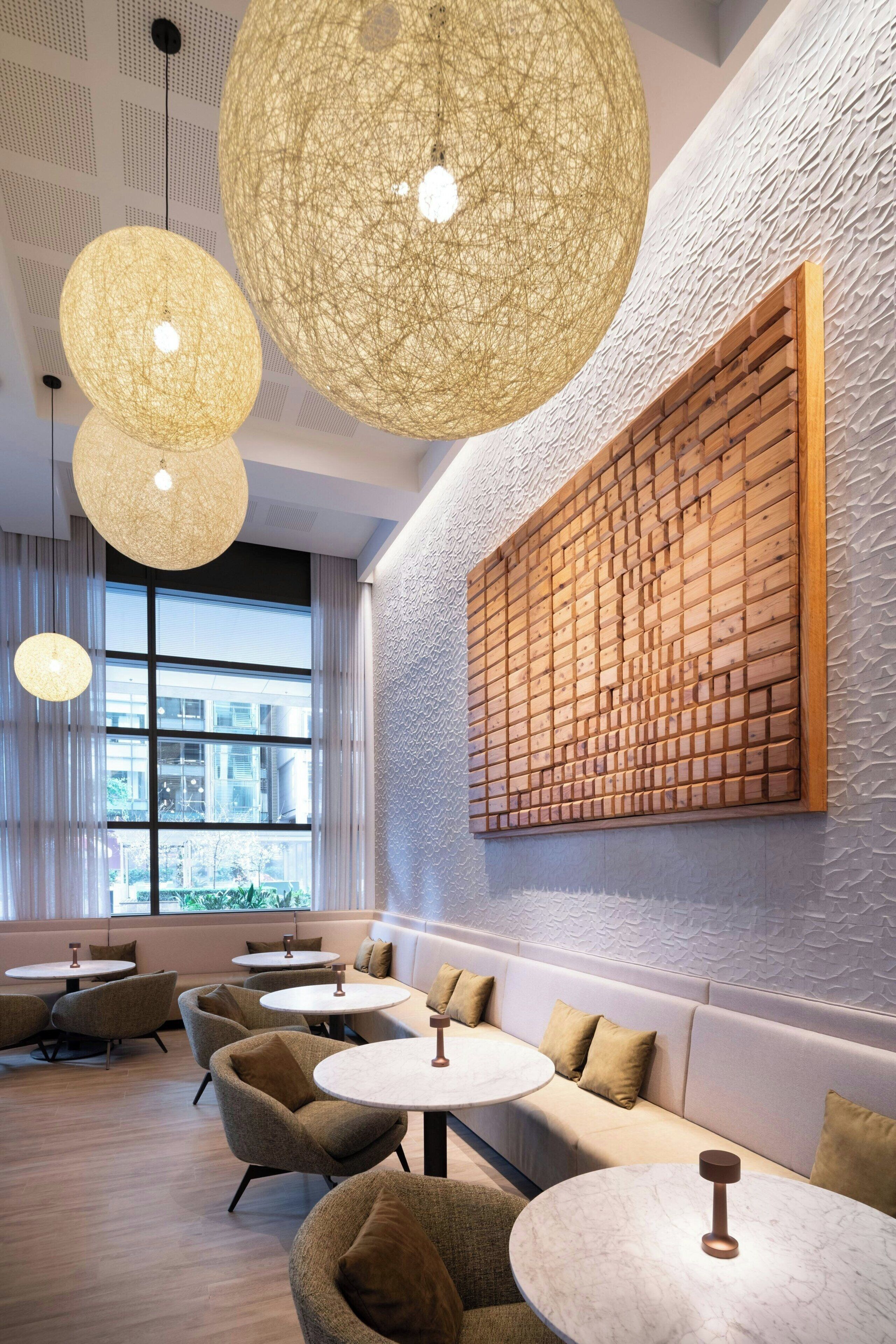 A modern interior with round tables, cushioned seating, and large hanging light fixtures.