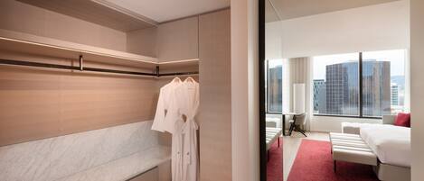 A modern hotel room with a large bed, a seating area, and a view of the cityscape.