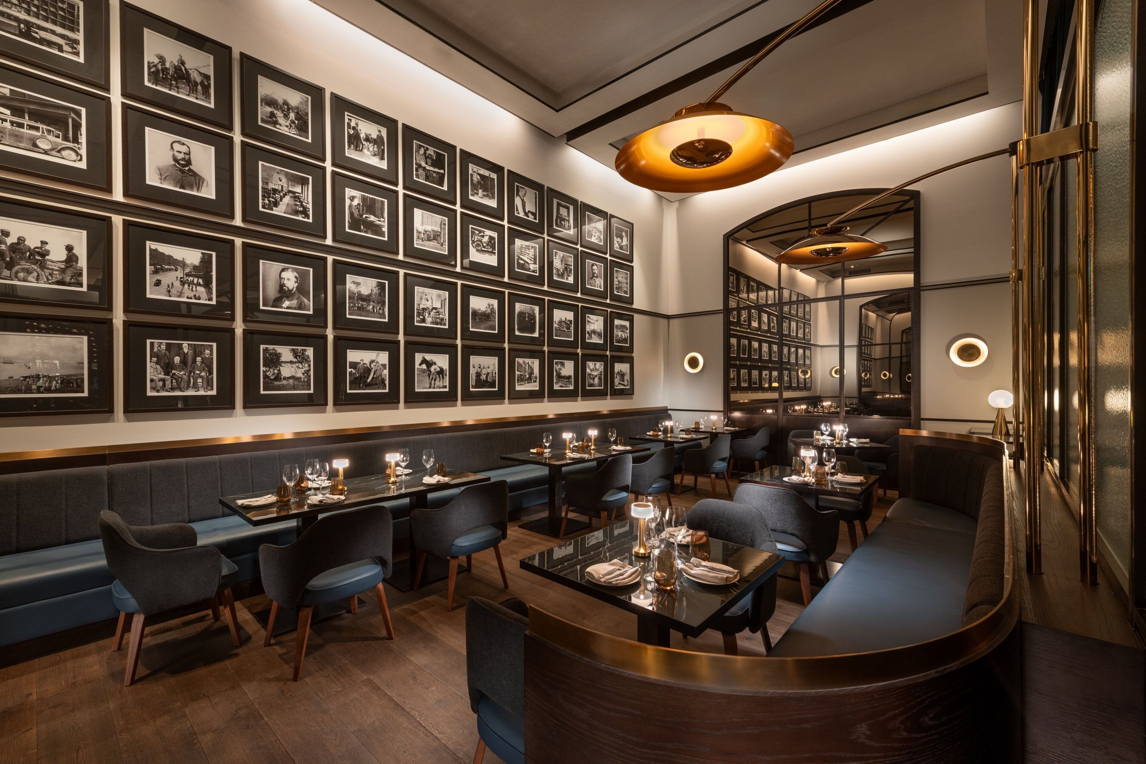 Un restaurant doté d’un long comptoir, de plusieurs tables et d’un mur recouvert de photographies encadrées.