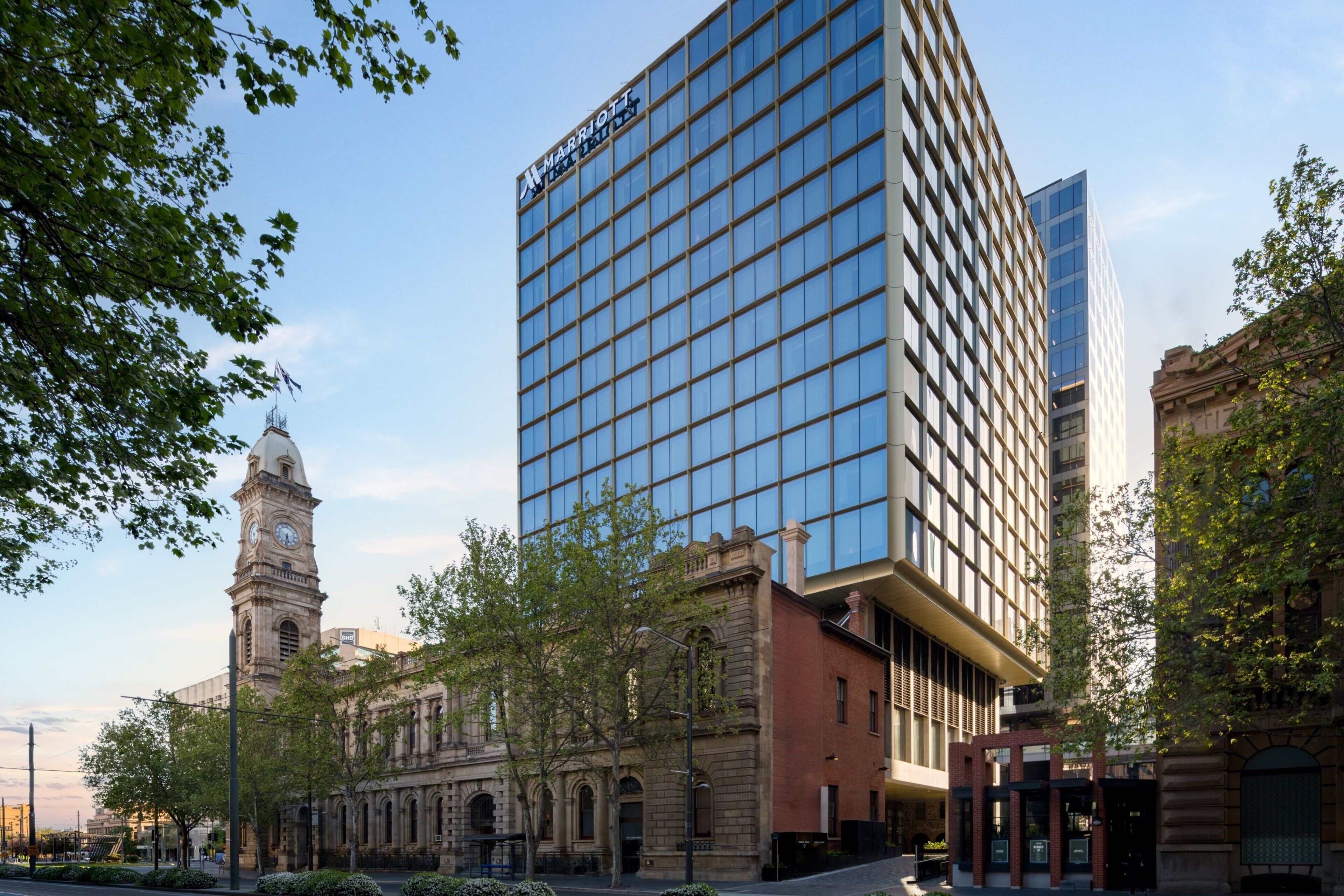 A modern hotel with a glass facade, a historic clock tower, and a mix of architectural styles.