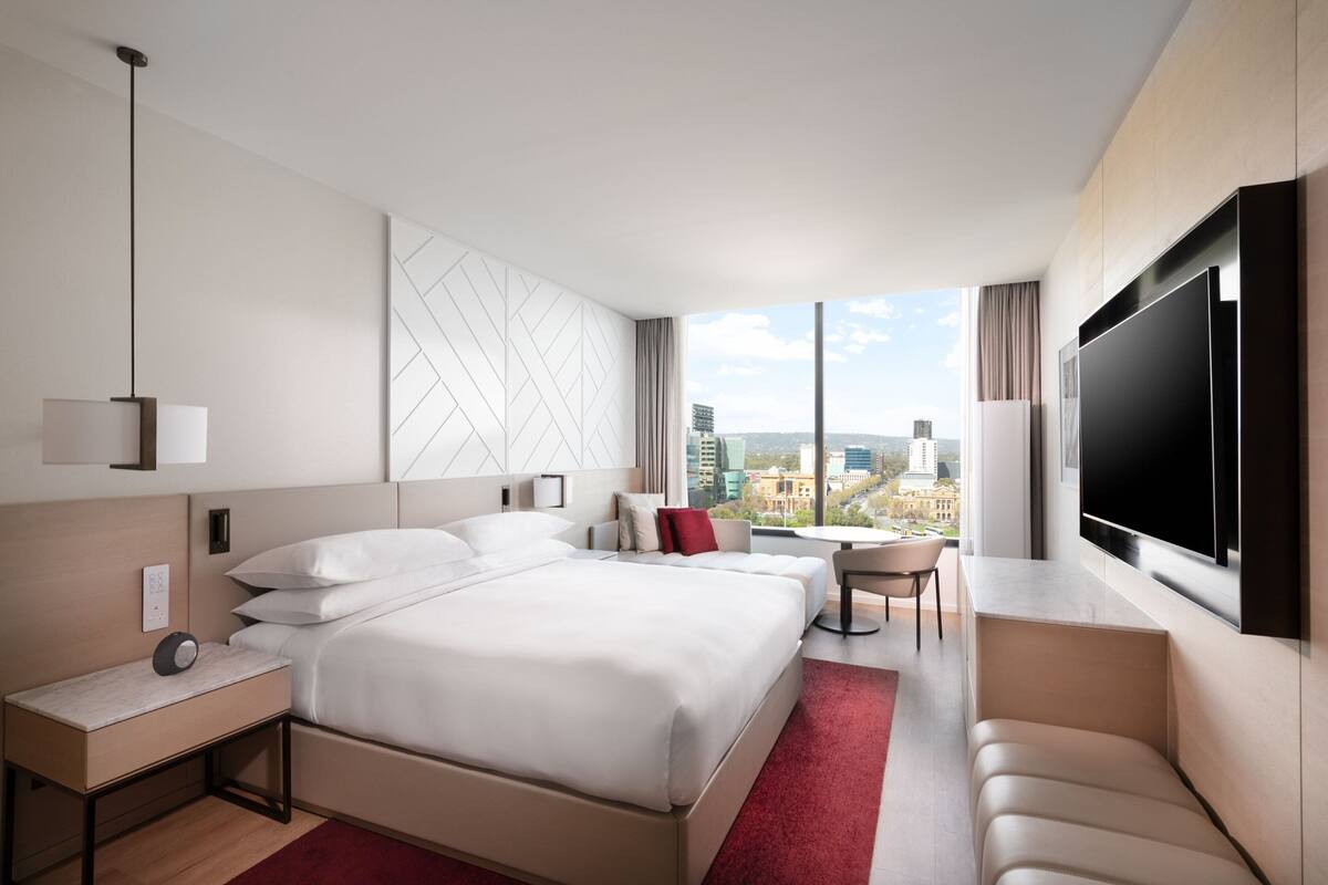 Moderni hotellihuone, jossa on suuri sänky, työpöytä, tuoli ja televisio.