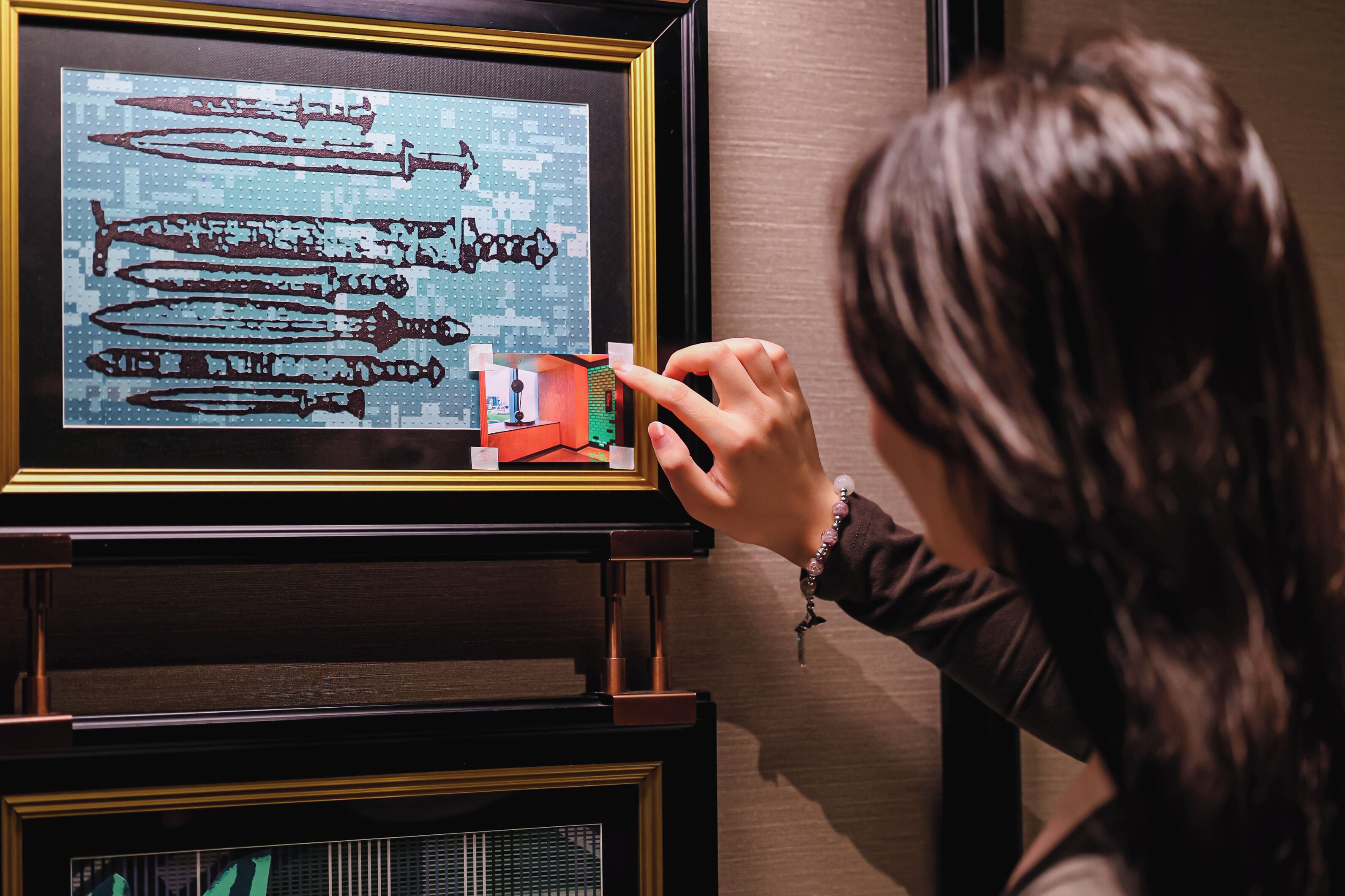 A person examining a framed artwork of musical instruments.
