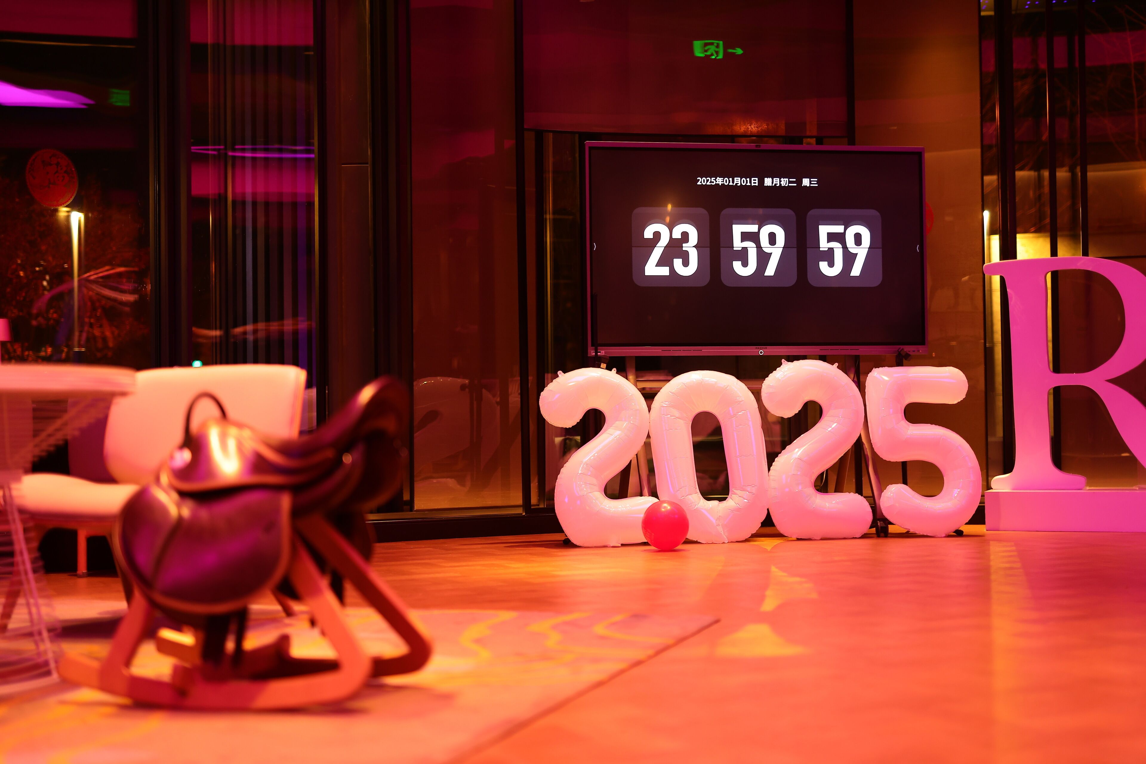 Ein Zimmer mit digitaler Uhr, die Datum und Uhrzeit anzeigt, einer großen Dekoration mit '2025' und einem einzigartigen Stuhldesign.
