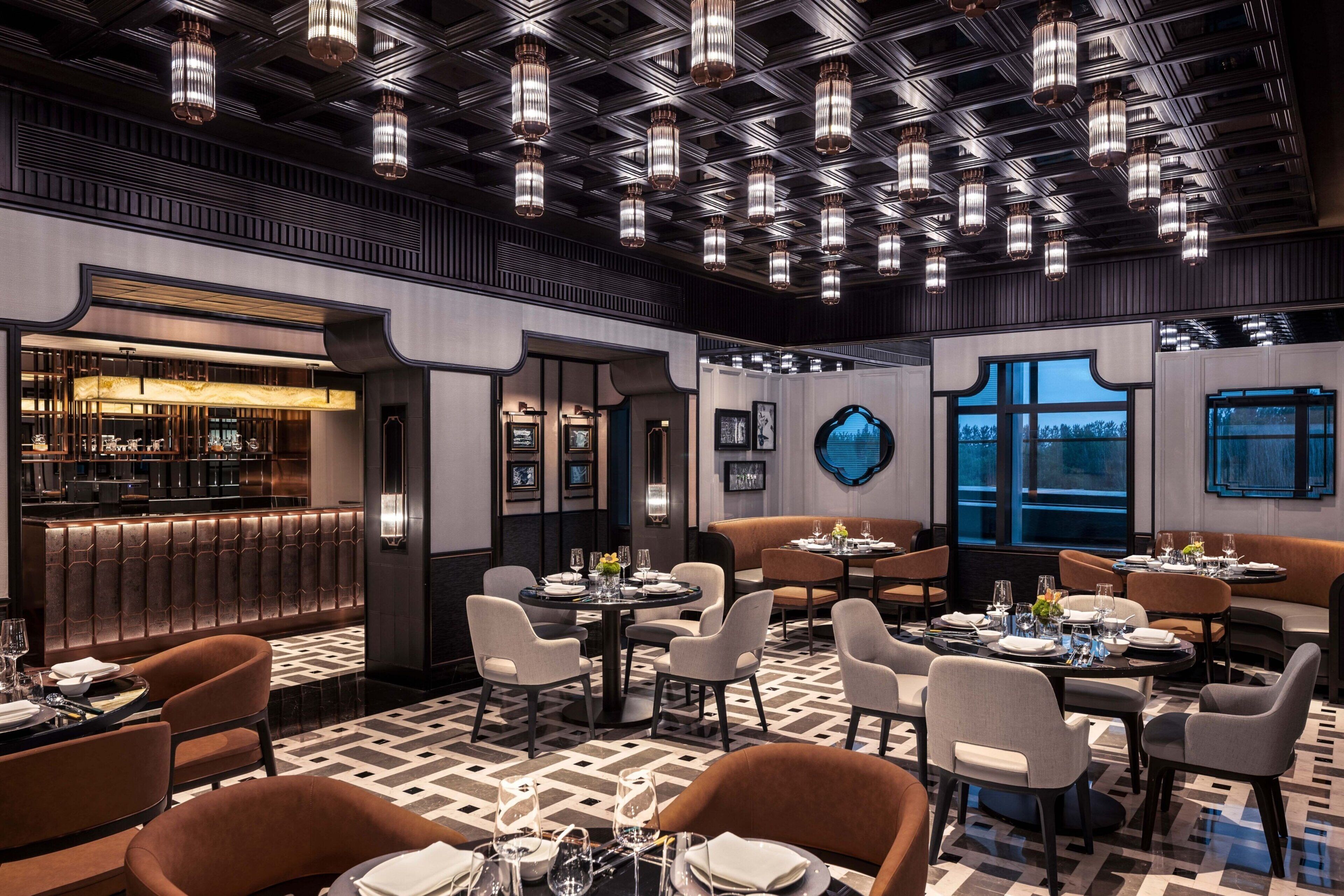 A modern dining area with round tables, cushioned seating, and pendant lighting.