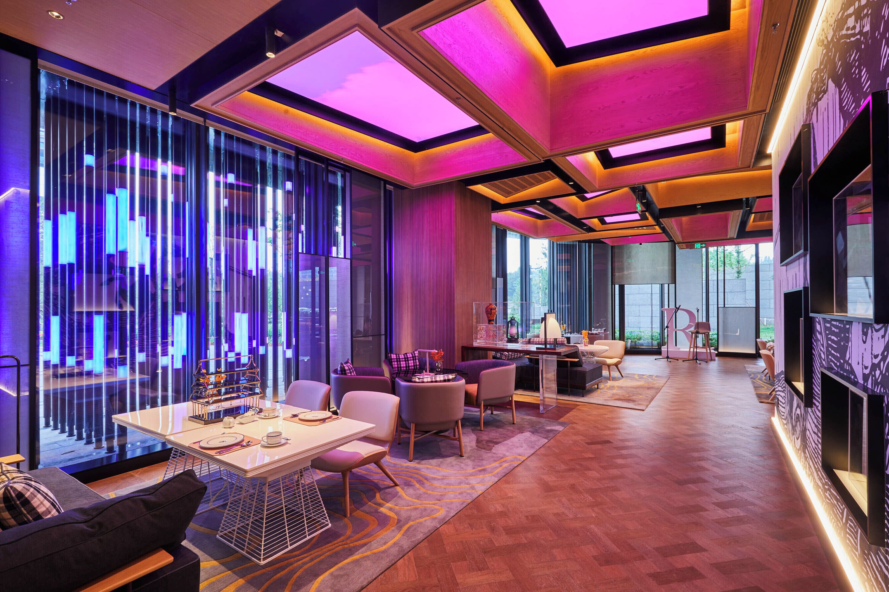 A modern hotel lobby with a dining area, seating, and a fireplace.