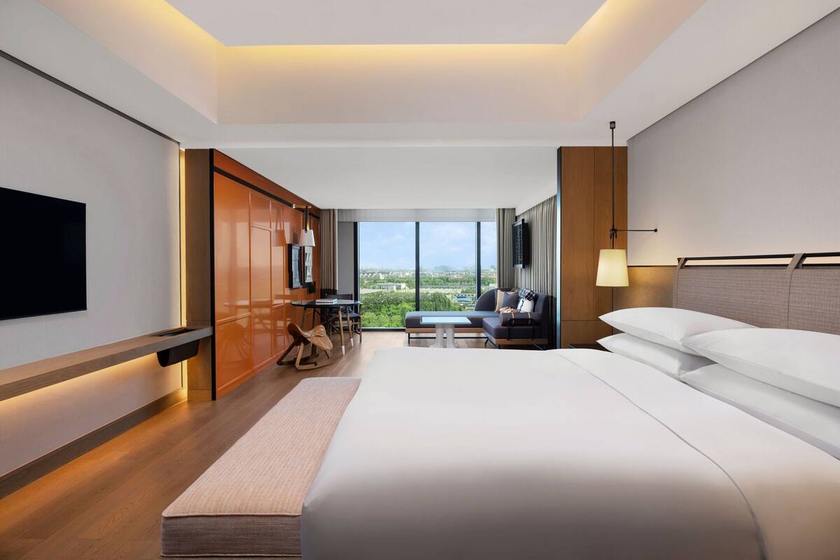 Une chambre d’hôtel moderne équipée d’un grand lit, d’un bureau, d’un canapé et d’une télévision.