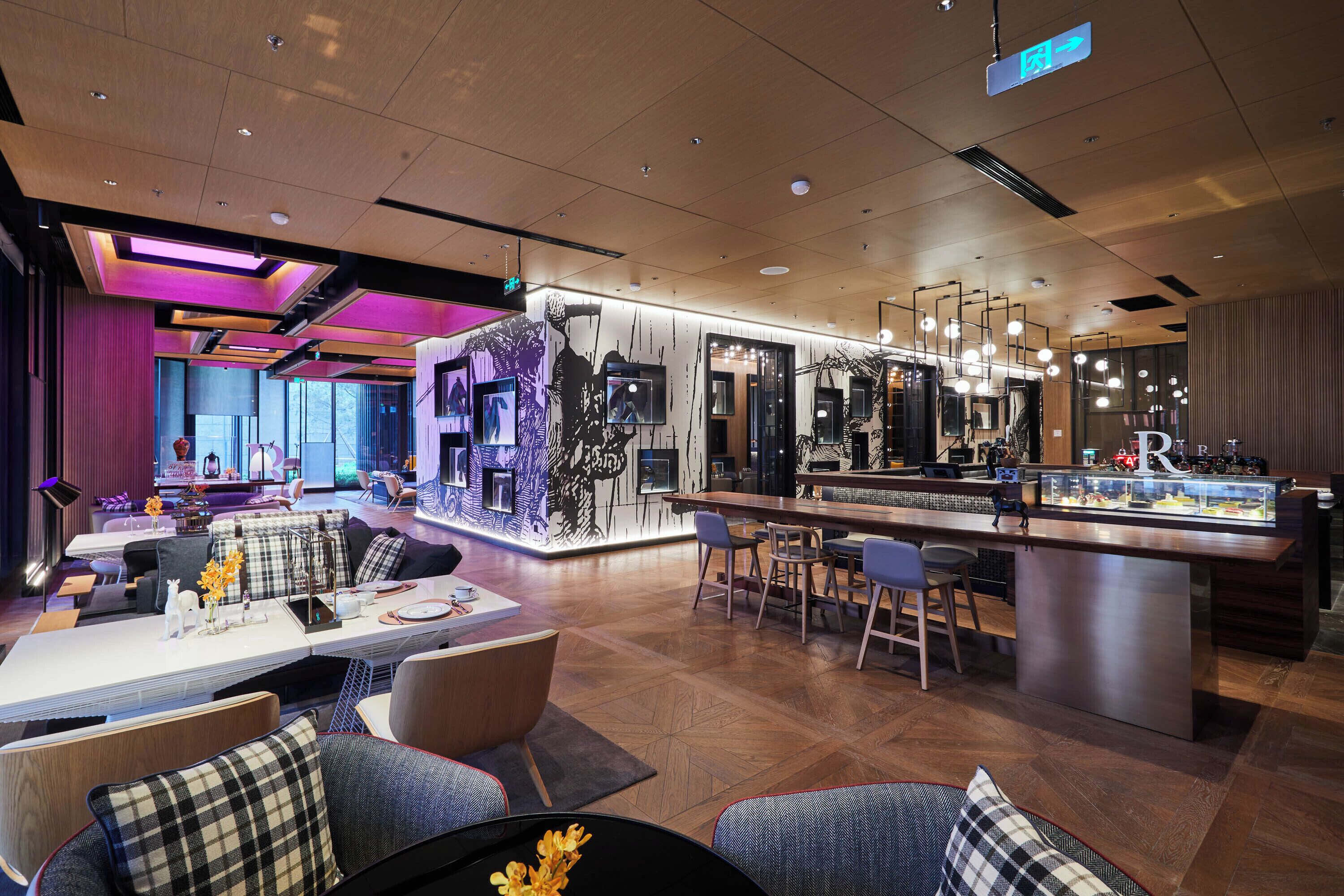 A modern hotel lobby with a bar area, seating arrangements, and a reception desk.