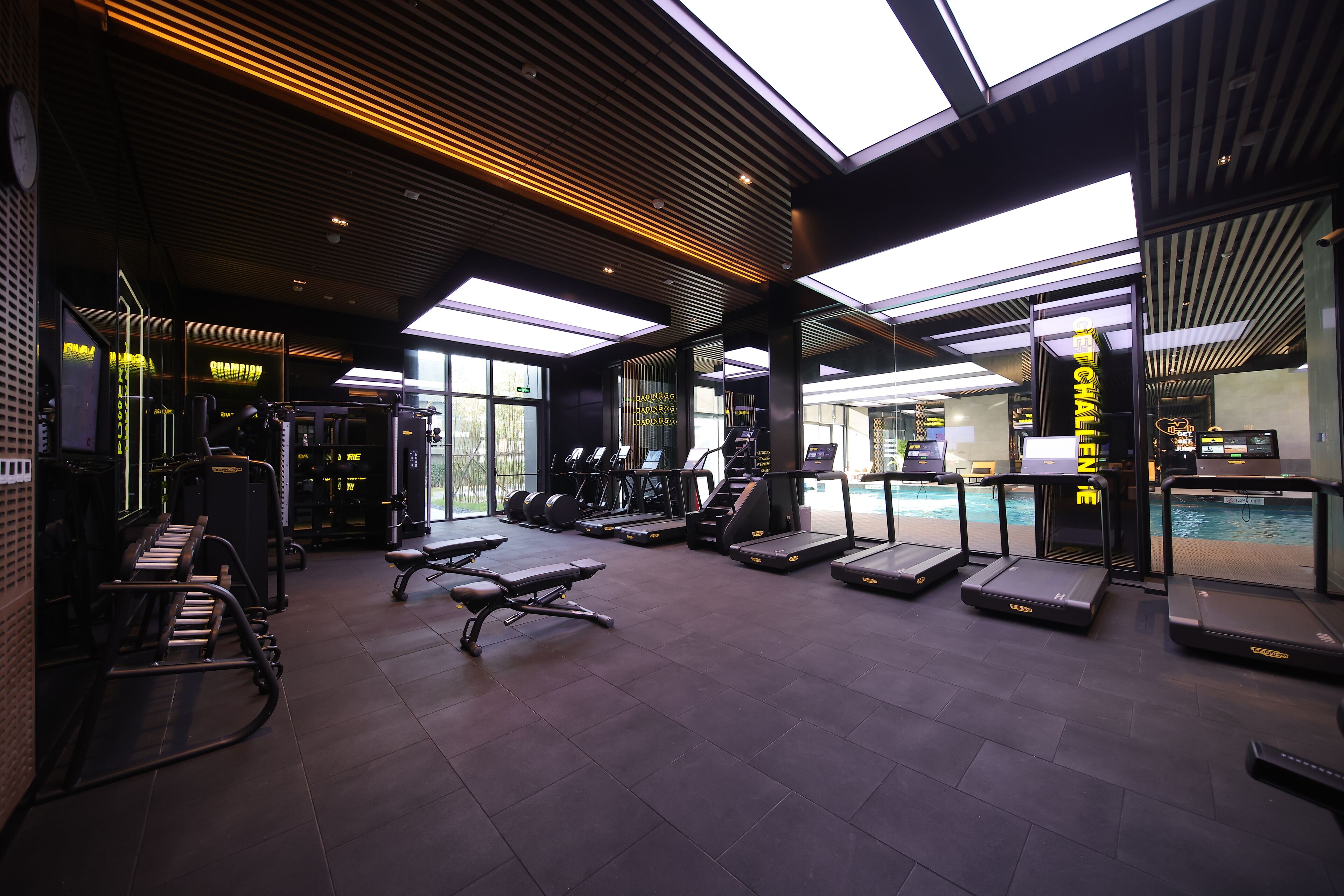 Une salle de sport équipée de tapis de course, d’appareils de musculation et d’un espace piscine.