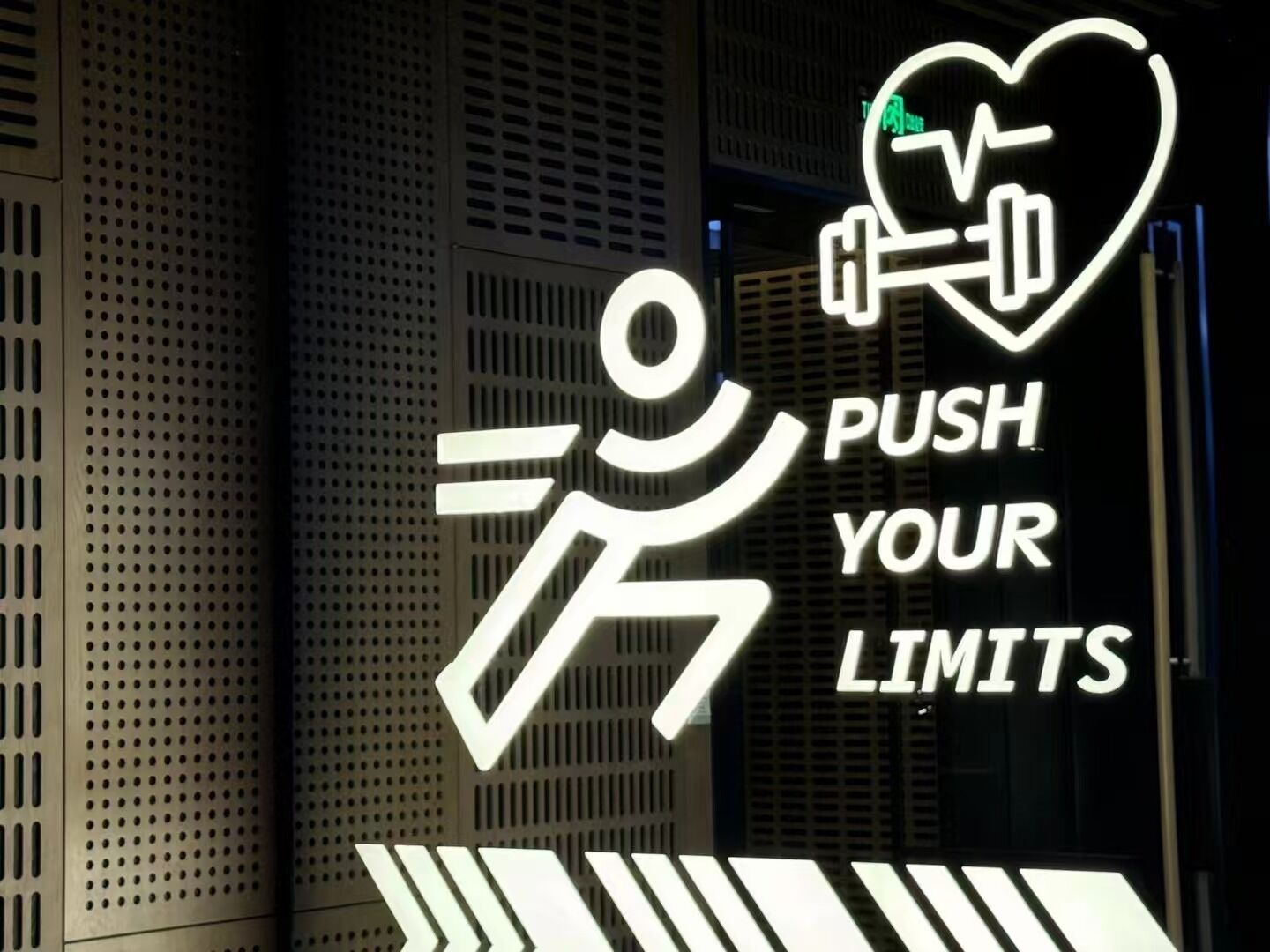A neon sign with a person lifting weights and a heart symbol, along with the text "PUSH YOUR LIMITS".