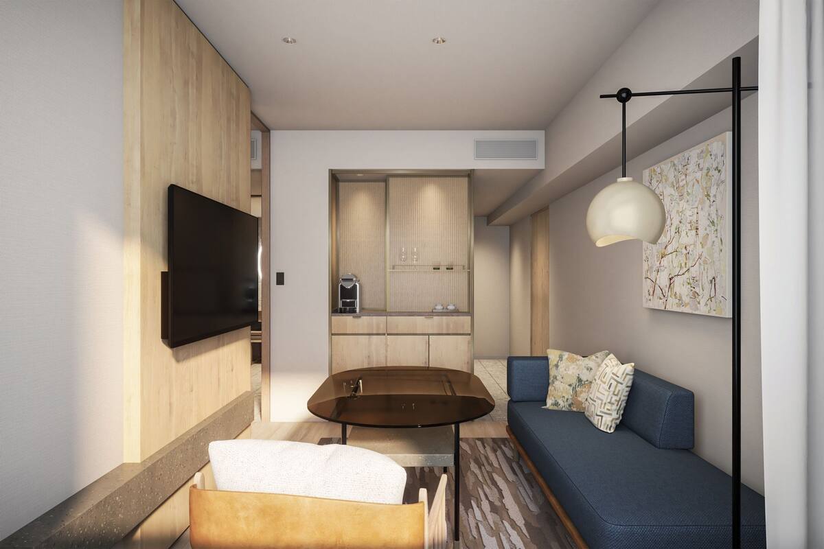 A modern living room with a sofa, a coffee table, and a flat-screen TV mounted on the wall.