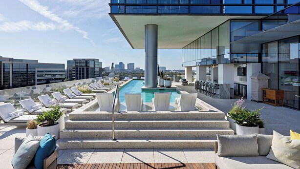 A rooftop pool area with lounge chairs and steps leading to the pool, surrounded by modern buildings. - HALL Park Hotel, Autograph Collection (Frisco)