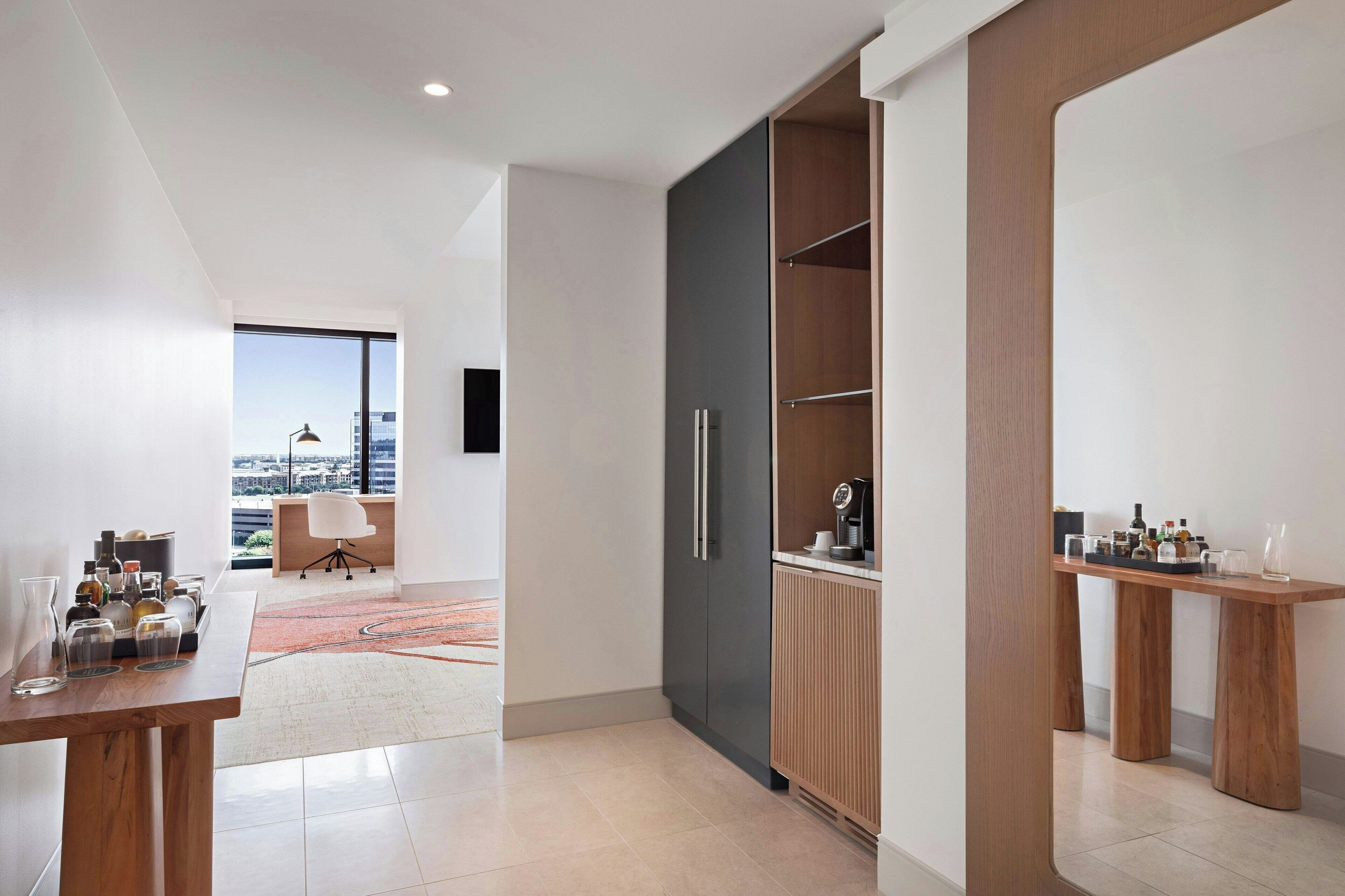 A modern kitchen with a large window, a dining area with a table, and a view of the city.