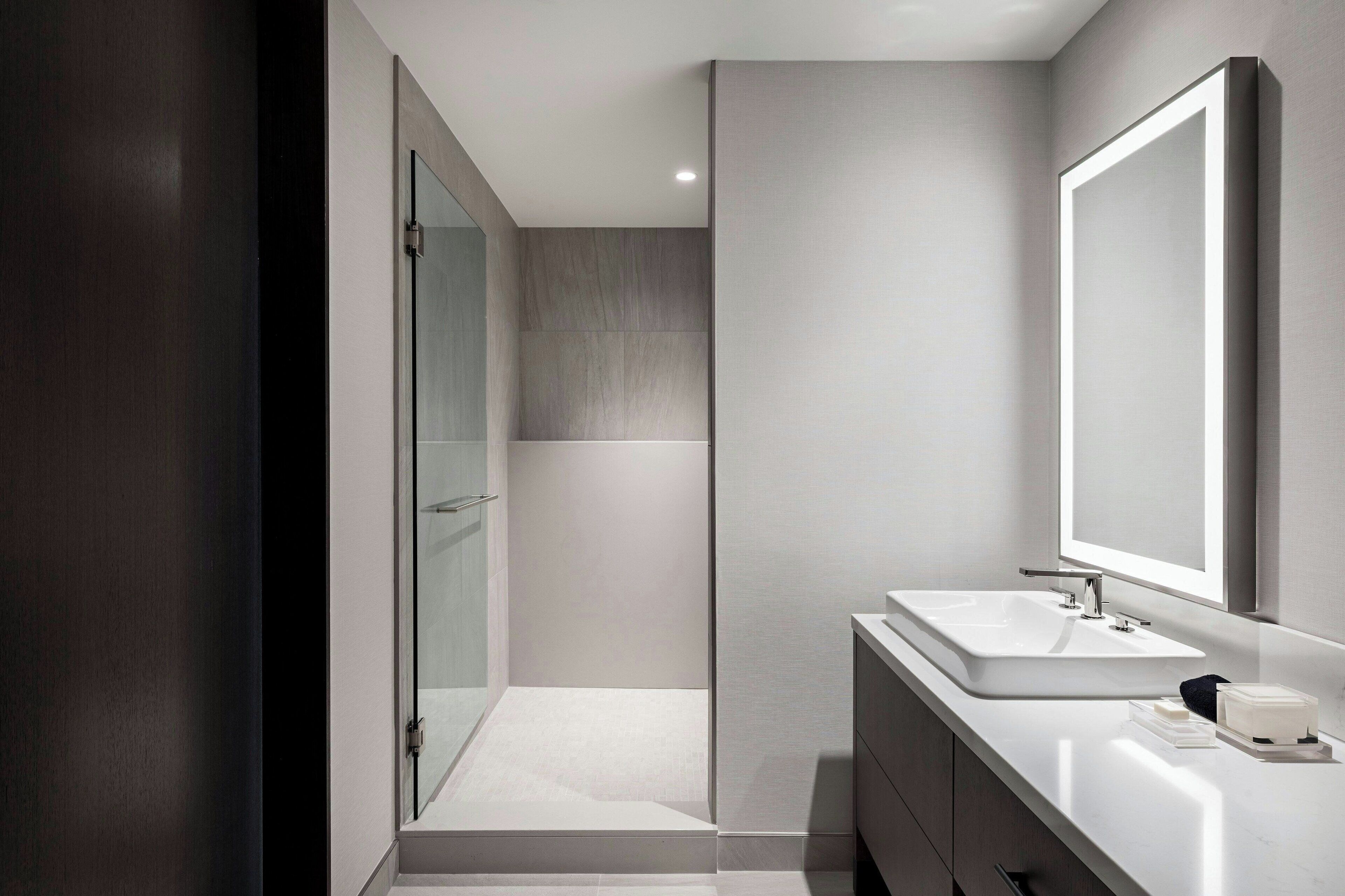 A modern bathroom with a glass shower, a large mirror, and a white sink.