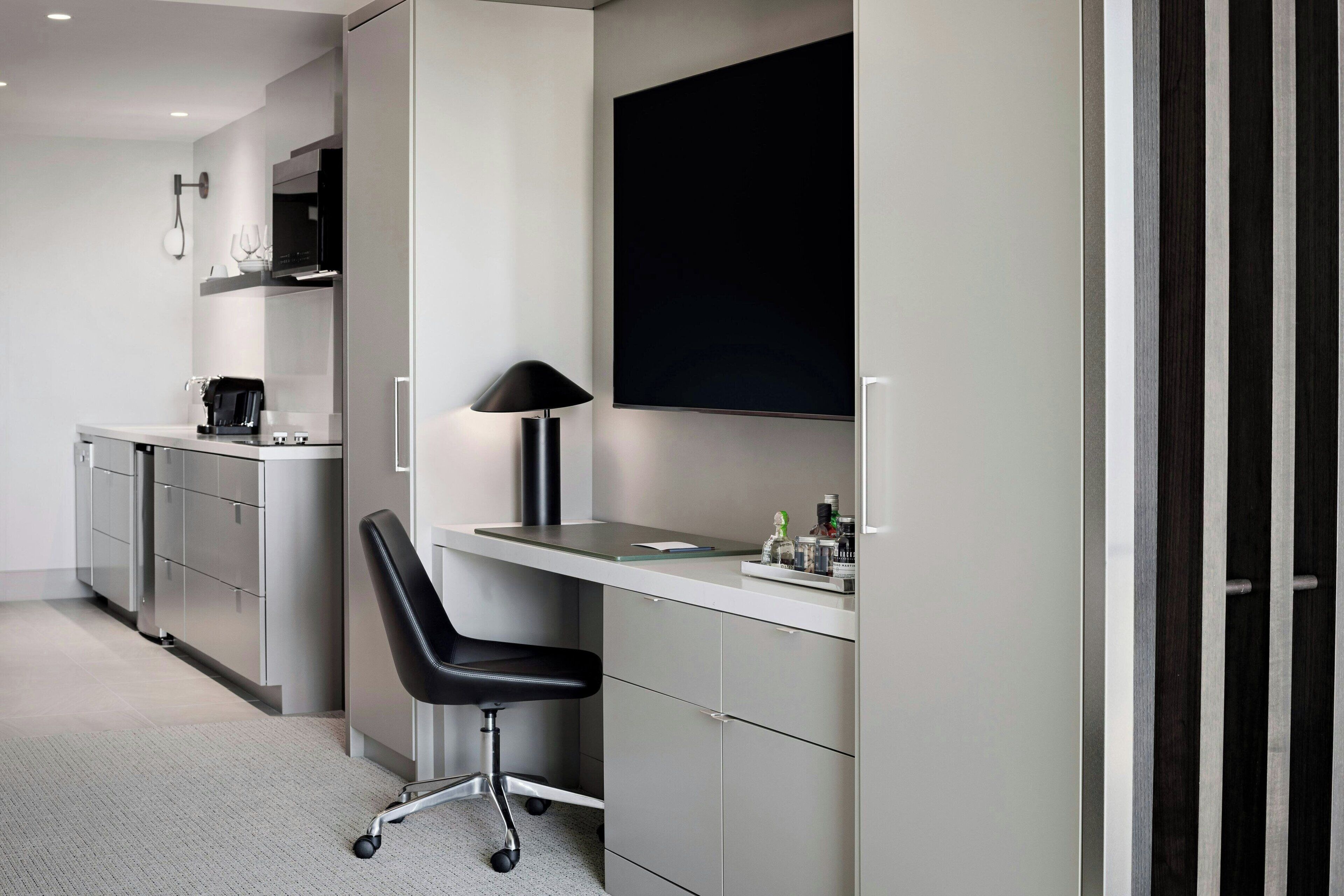A modern kitchen with a built-in stove, a coffee machine, and a black chair.