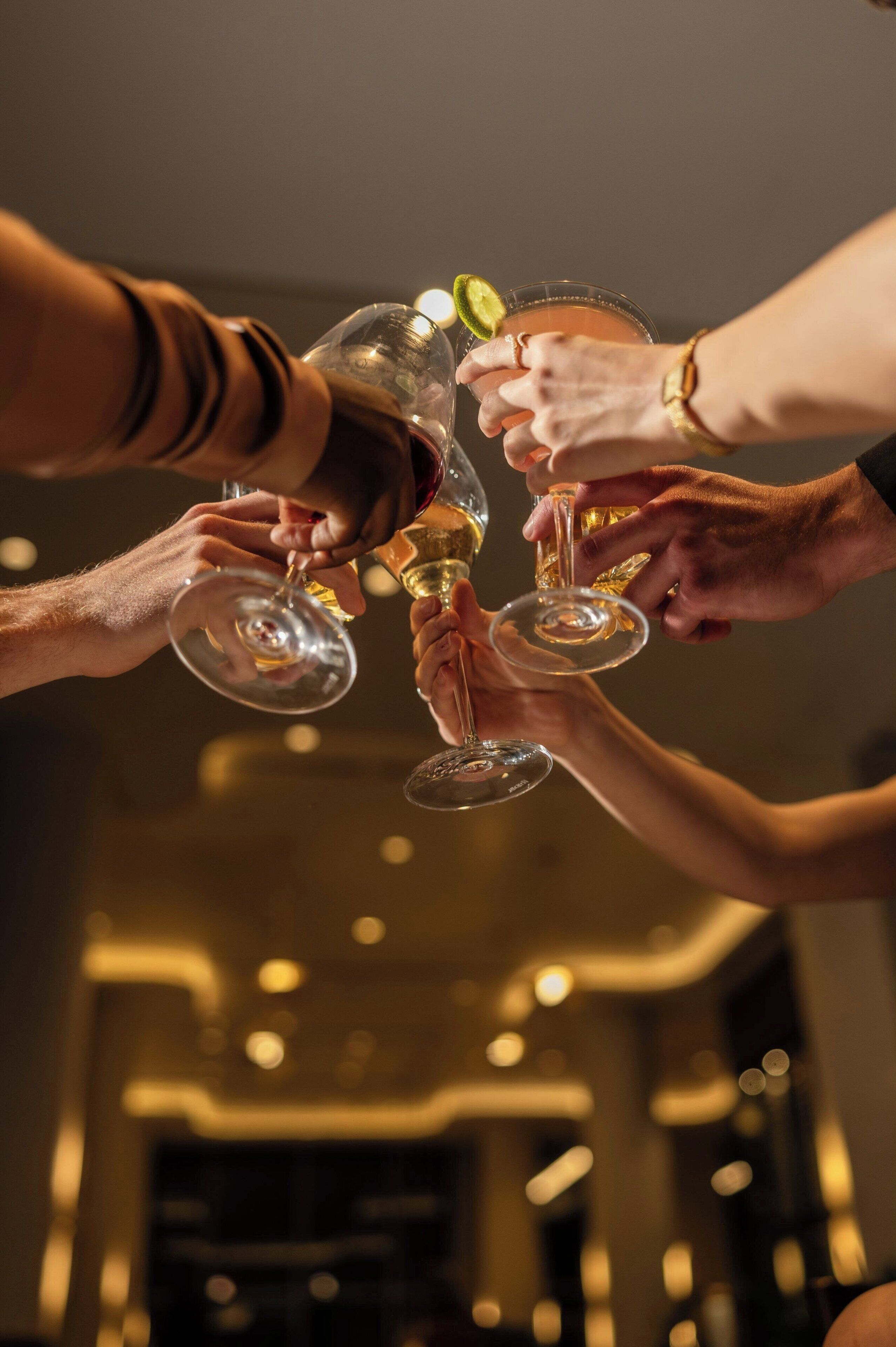 A group of people toasting with wine glasses in a dimly lit room.