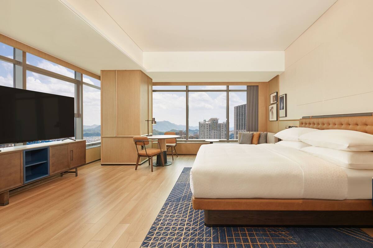 Una habitación de hotel moderna con una cama grande, un escritorio y un televisor.