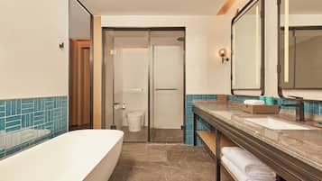 A modern bathroom with a bathtub, two sinks, a glass shower enclosure, and a toilet.