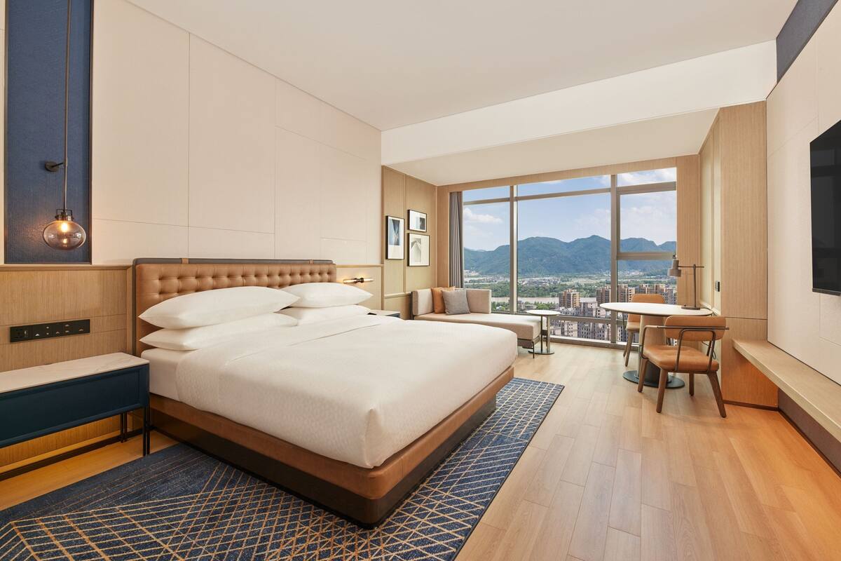 Una habitación de hotel moderna con una cama grande, un escritorio y vistas a la ciudad.