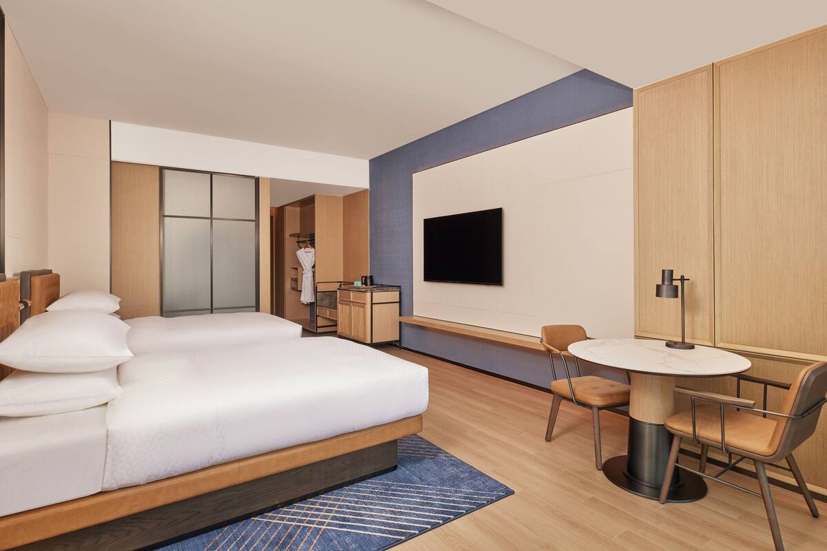 Una habitación de hotel moderna con una cama grande, un escritorio y un televisor.