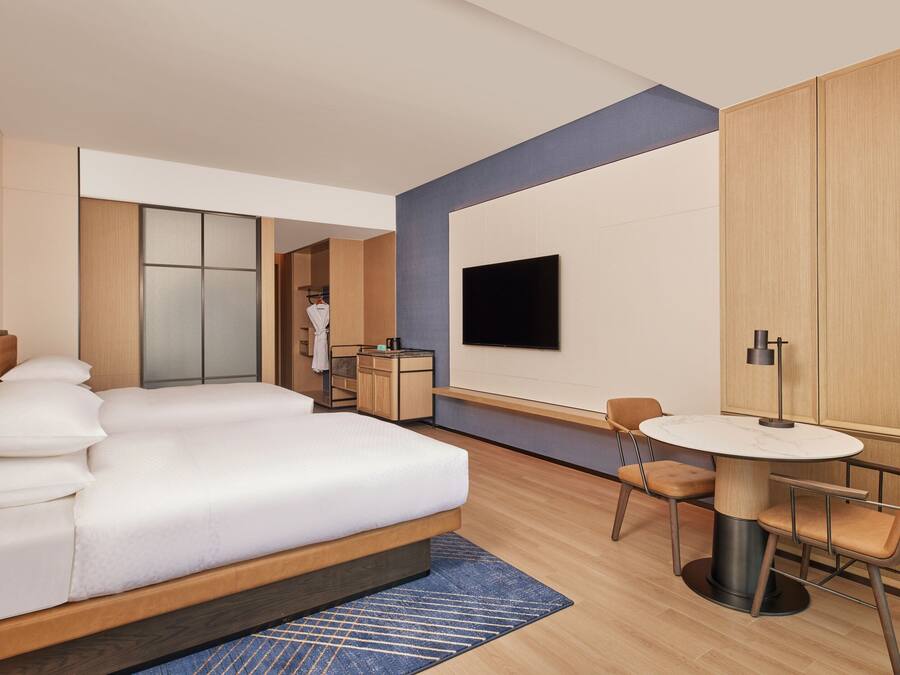 A modern hotel room with a large bed, a desk, and a TV.