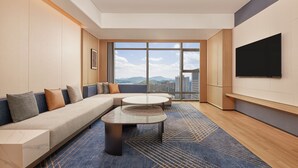 A modern hotel room with a large window, a sofa, a coffee table, and a flat-screen TV. - Four Points By Sheraton Linhai (Taizhou)
