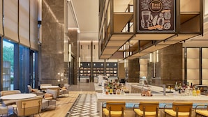 A modern bar area with seating and a bar counter displaying various bottles. - Four Points By Sheraton Linhai (Taizhou)