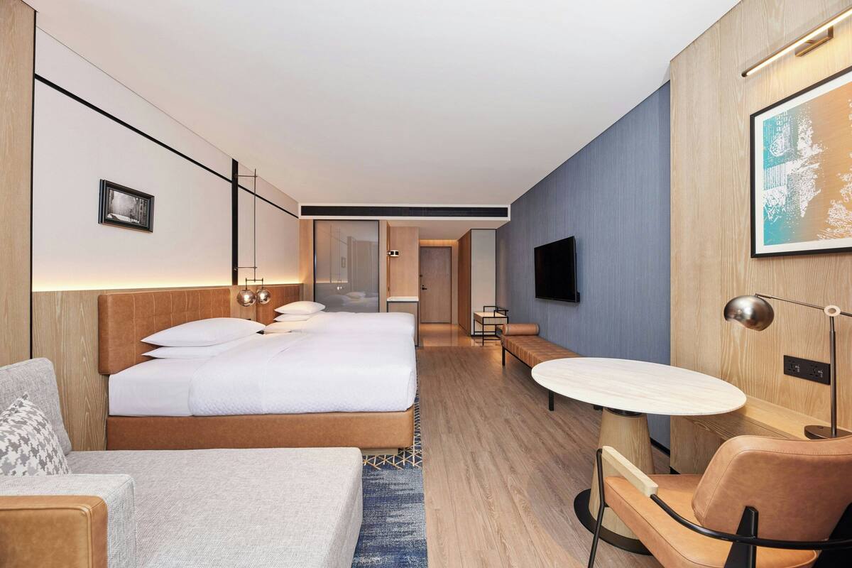 Ein modernes Hotelzimmer mit einem großen Bett, einem Schreibtisch, einem Stuhl und einem Fernseher.