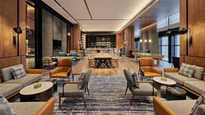 Un área de estar moderna con mesa de billar, asientos cómodos y una zona de bar.