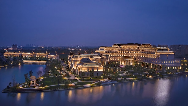 Un hotel grande e iluminado con varias construcciones y un lago al frente.