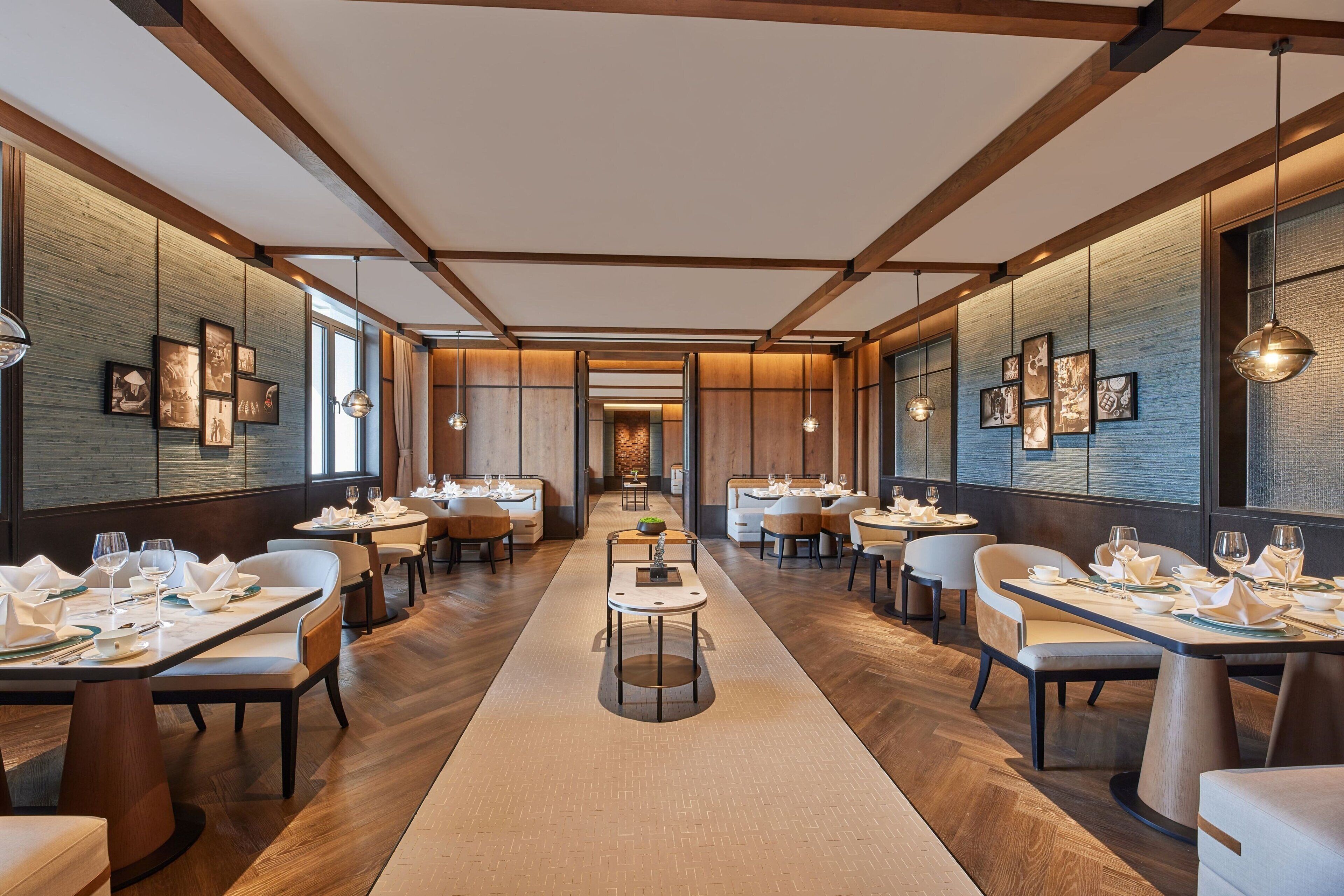 Un ristorante moderno con travi in legno, tavoli lunghi e quadri appesi alle pareti.